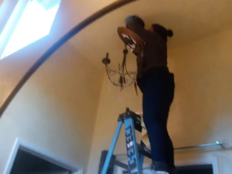 Electrician installing a chandelier in a Tredyffrin residence